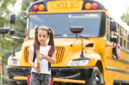 Girl with backpack near yellow school bus. Transport for students