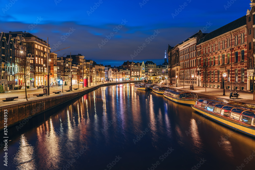 Amsterdam cityscape after sunset, beautiful old European city reflected in Amstel river in evening, Netherlands.