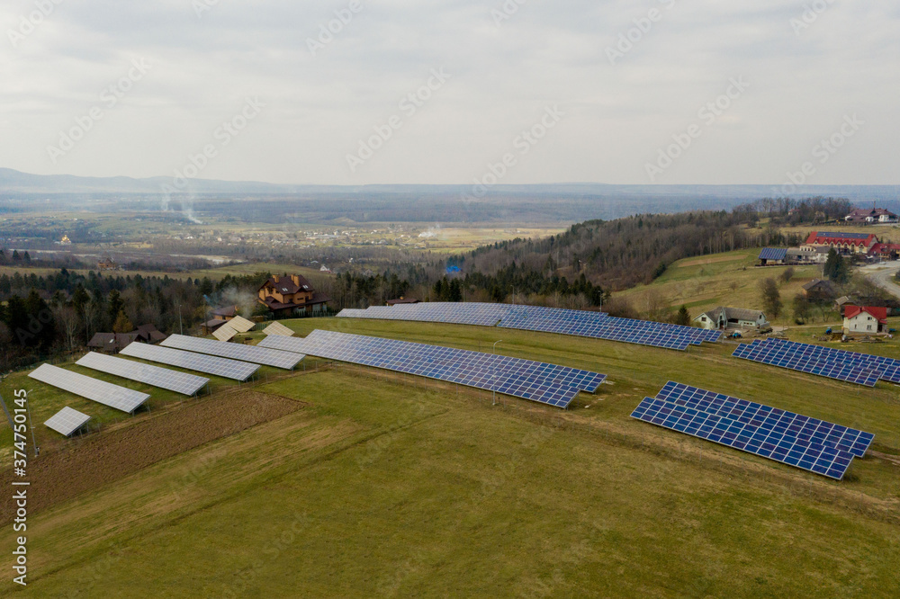 Aerial view of blue solar photo voltaic panels system producing renewable clean energy on rural landscape