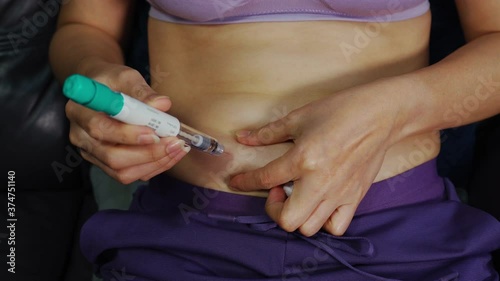 woman use pre-filled pen syringe for take the FSH (Follicle Stimulating Hormone) into the abdominal  to stimulate the ovaries photo