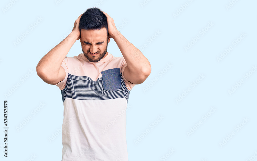 Young handsome man wearing casual clothes suffering from headache desperate and stressed because pain and migraine. hands on head. Young handsome man wearing casual clothes suffering from headache desperate and stressed because pain and migraine. hands on head.