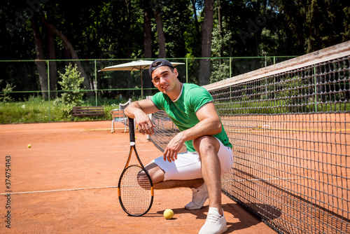 Portrait of young athletic man on tennis court. © romaset