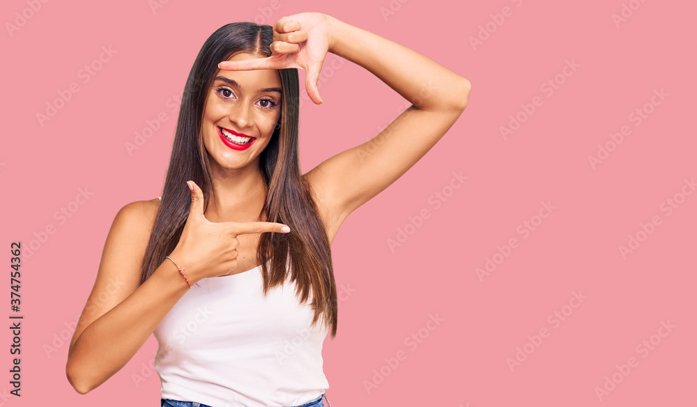 Young hispanic woman wearing casual clothes smiling making frame with hands and fingers with happy face. creativity and photography concept. Young hispanic woman wearing casual clothes smiling making frame with hands and fingers with happy face. creativity and photography concept.