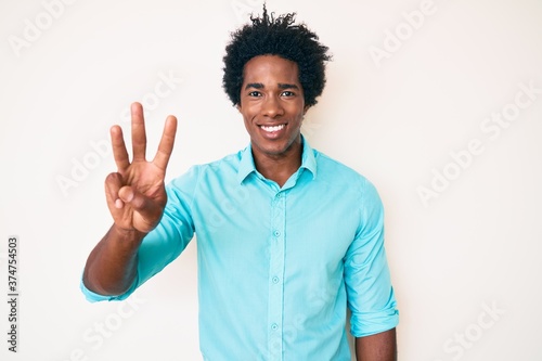 Handsome african american man with afro hair wearing casual clothes showing and pointing up with fingers number three while smiling confident and happy.