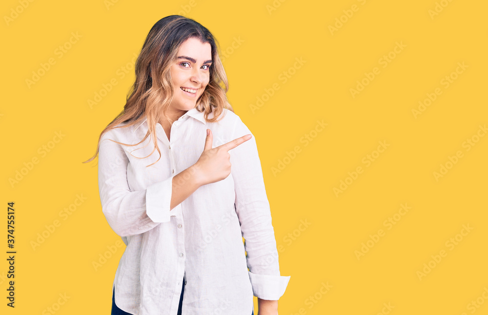 Young caucasian woman wearing casual clothes cheerful with a smile of face pointing with hand and finger up to the side with happy and natural expression on face Young caucasian woman wearing casual clothes cheerful with a smile of face pointing with hand and finger up to the side with happy and natural expression on face