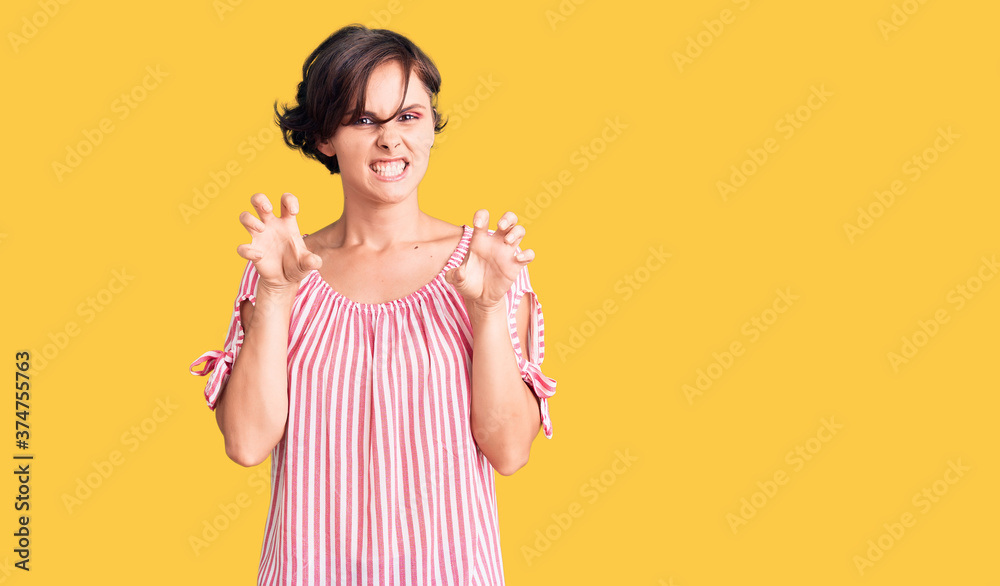 Beautiful young woman with short hair wearing casual summer clothes smiling funny doing claw gesture as cat, aggressive and sexy expression Beautiful young woman with short hair wearing casual summer clothes smiling funny doing claw gesture as cat, aggressive and sexy expression