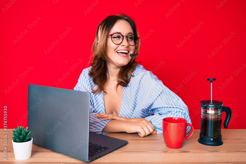 Young beautiful caucasian woman working at the office wearing operator headset looking to side, relax profile pose with natural face and confident smile. Young beautiful caucasian woman working at the office wearing operator headset looking to side, relax profile pose with natural face and confident smile.