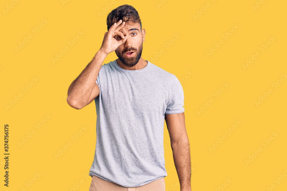 Fototapeta premium Young hispanic man wearing casual clothes doing ok gesture shocked with surprised face, eye looking through fingers. unbelieving expression.