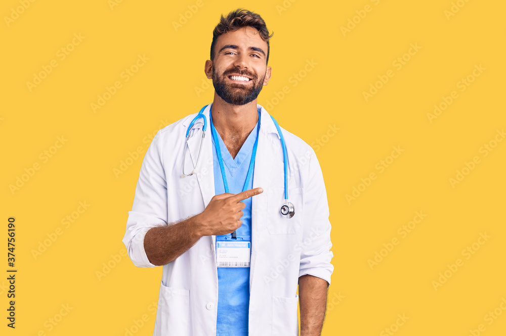 Young hispanic man wearing doctor uniform and stethoscope cheerful with a smile of face pointing with hand and finger up to the side with happy and natural expression on face Young hispanic man wearing doctor uniform and stethoscope cheerful with a smile of face pointing with hand and finger up to the side with happy and natural expression on face