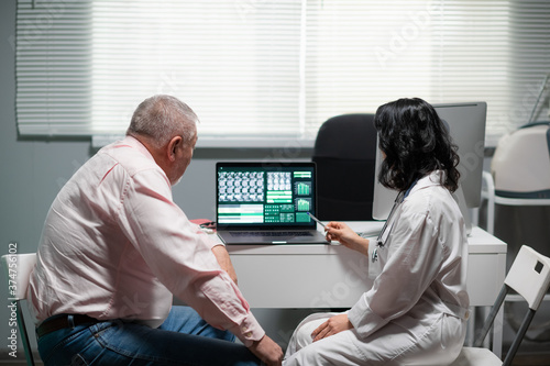 A man and a woman are looking at the x-ray on the monitor of the lap top. photo