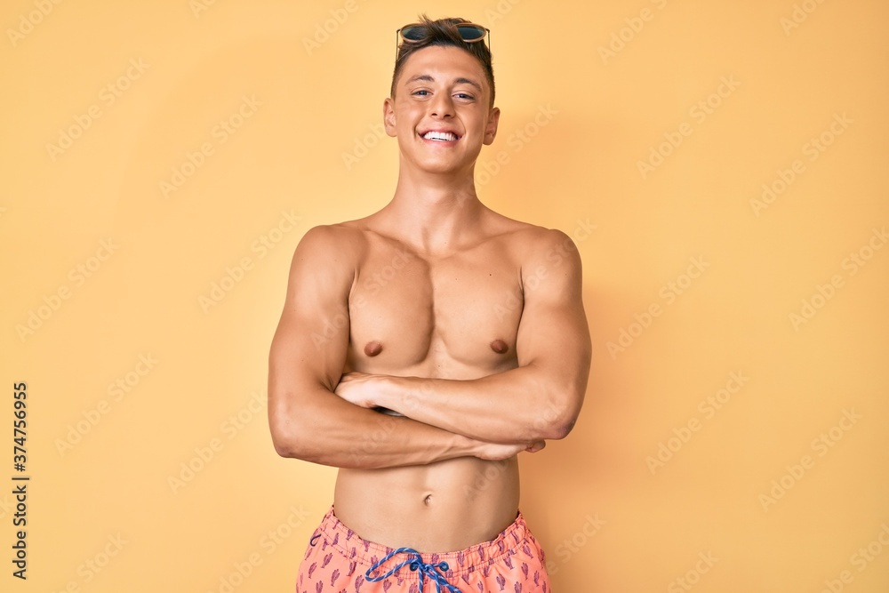 Young hispanic boy wearing swimwear shirtless happy face smiling with crossed arms looking at the camera. positive person.