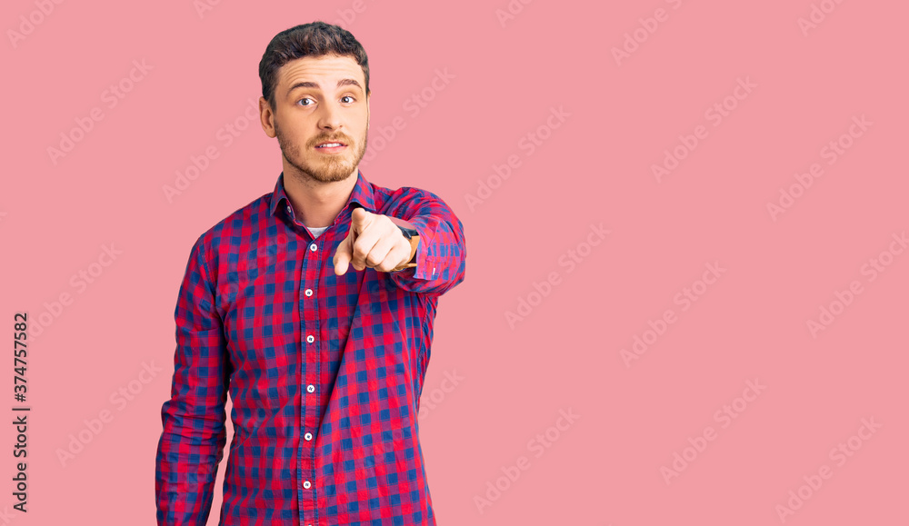 Handsome young man with bear wearing casual shirt pointing displeased and frustrated to the camera, angry and furious with you Handsome young man with bear wearing casual shirt pointing displeased and frustrated to the camera, angry and furious with you
