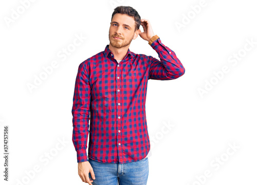 Handsome young man with bear wearing casual shirt confuse and wondering about question. uncertain with doubt, thinking with hand on head. pensive concept.