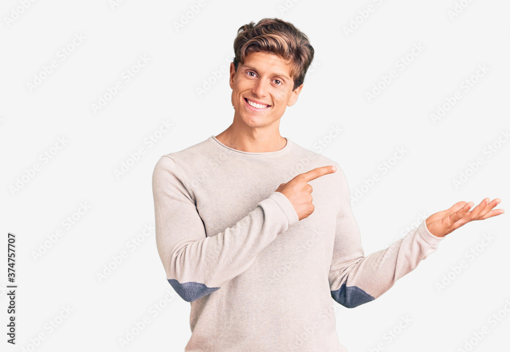 Young handsome man wearing casual clothes amazed and smiling to the camera while presenting with hand and pointing with finger. Young handsome man wearing casual clothes amazed and smiling to the camera while presenting with hand and pointing with finger.