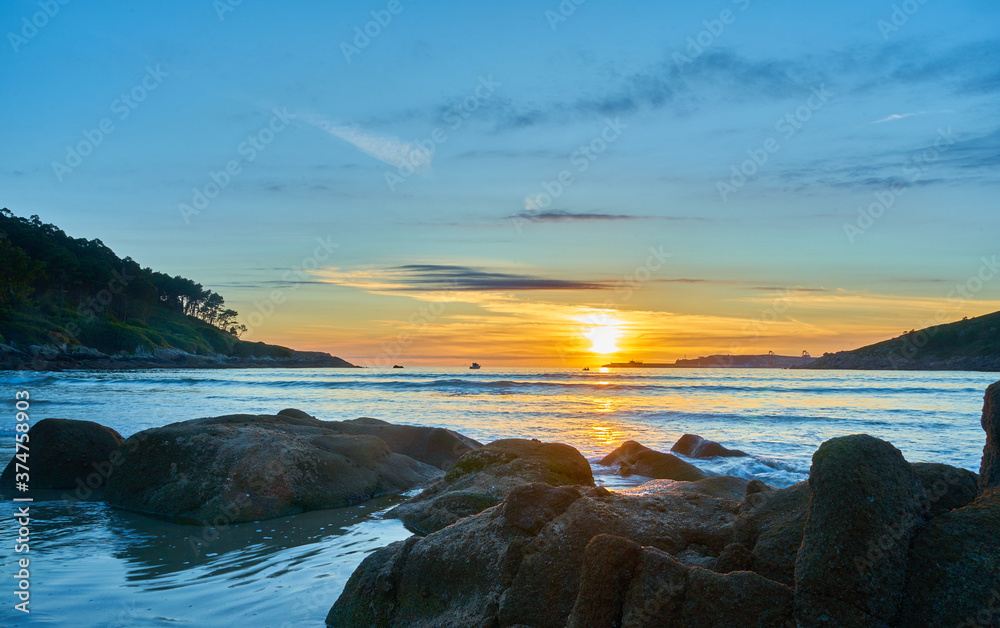 Beautiful photo of a sunset on Chanteiro beach, with the rocks illuminated by the sun. Spain