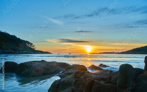 Beautiful photo of a sunset on Chanteiro beach, with the rocks illuminated by the sun. Spain © Nedrofly