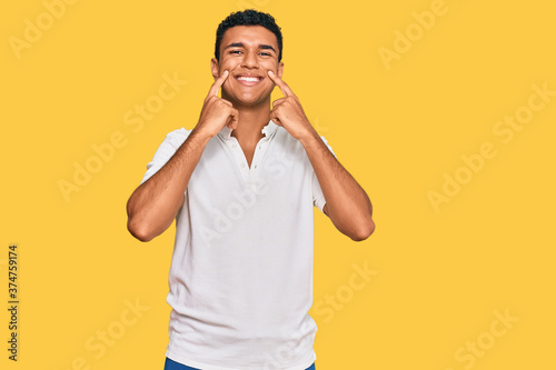 Young arab man wearing casual clothes smiling with open mouth, fingers pointing and forcing cheerful smile © Krakenimages.com
