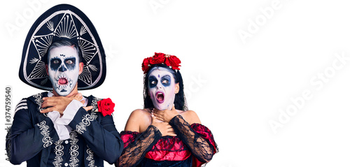 Young couple wearing mexican day of the dead costume over background shouting suffocate because painful strangle. health problem. asphyxiate and suicide concept.