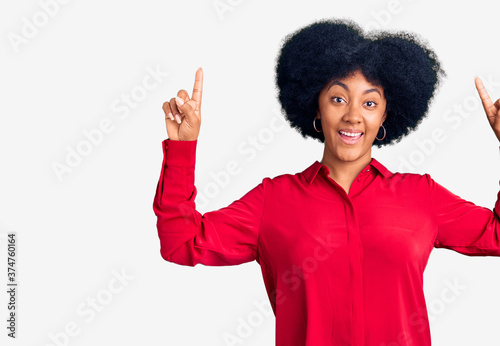 Young african american girl wearing casual clothes smiling amazed and surprised and pointing up with fingers and raised arms.
