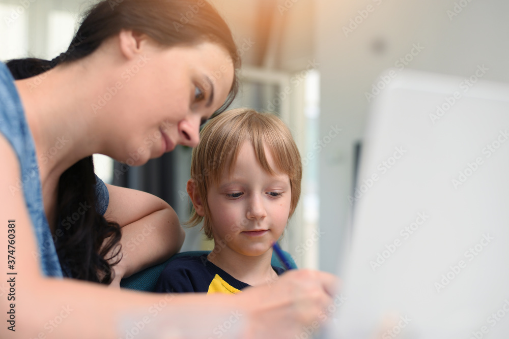 Coronavirus Outbreak. Lockdown and school closures. Mother helping her son studying online classes at home. COVID-19 pandemic forces children and teachers online learning Coronavirus Outbreak. Lockdown and school closures. Mother helping her son studying online classes at home. COVID-19 pandemic forces children and teachers online learning