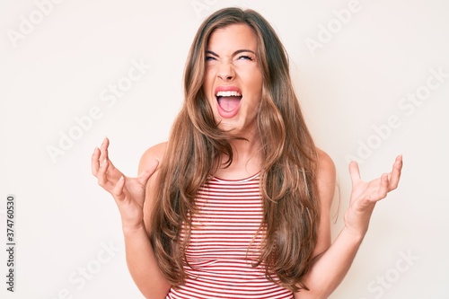 Beautiful young caucasian woman wearing casual clothes crazy and mad shouting and yelling with aggressive expression and arms raised. frustration concept.