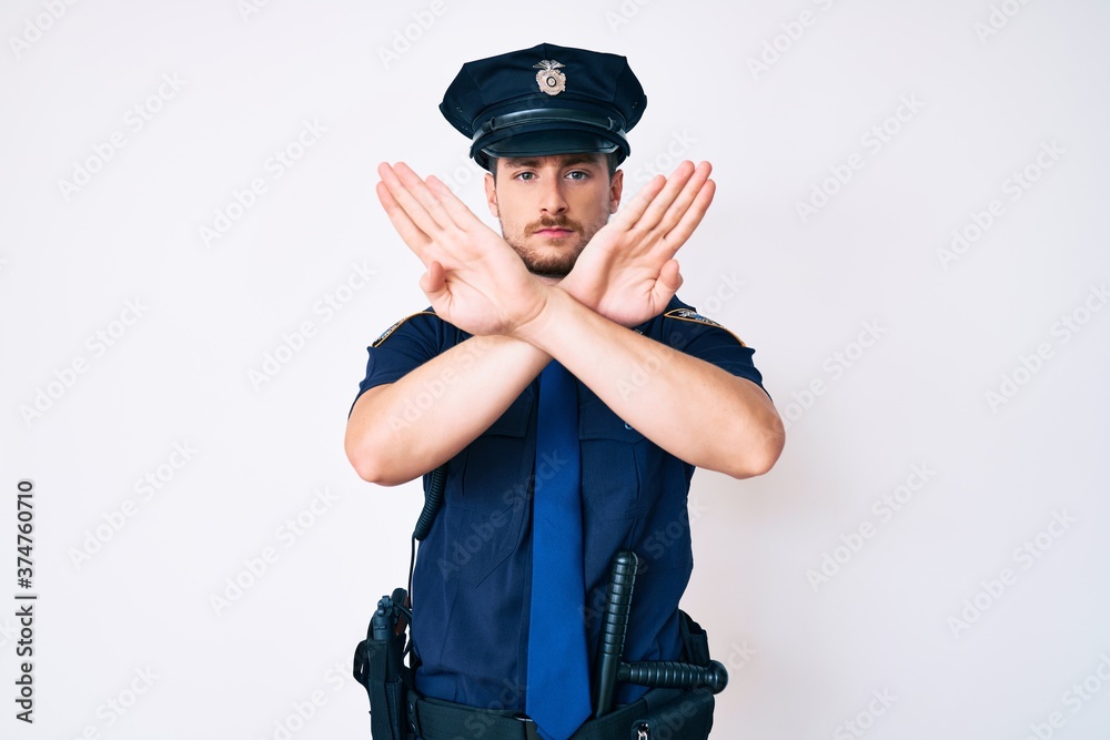 Young caucasian man wearing police uniform rejection expression crossing arms doing negative sign, angry face Young caucasian man wearing police uniform rejection expression crossing arms doing negative sign, angry face