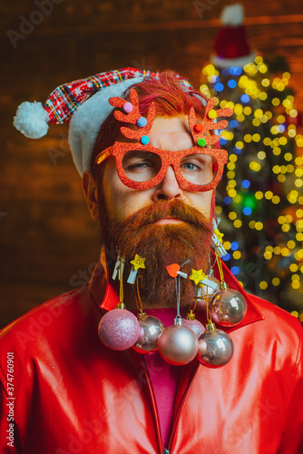 Portrait of handsome Santa man indoors with Christmas gift. New year concept. Santa posing on vintage wooden background.