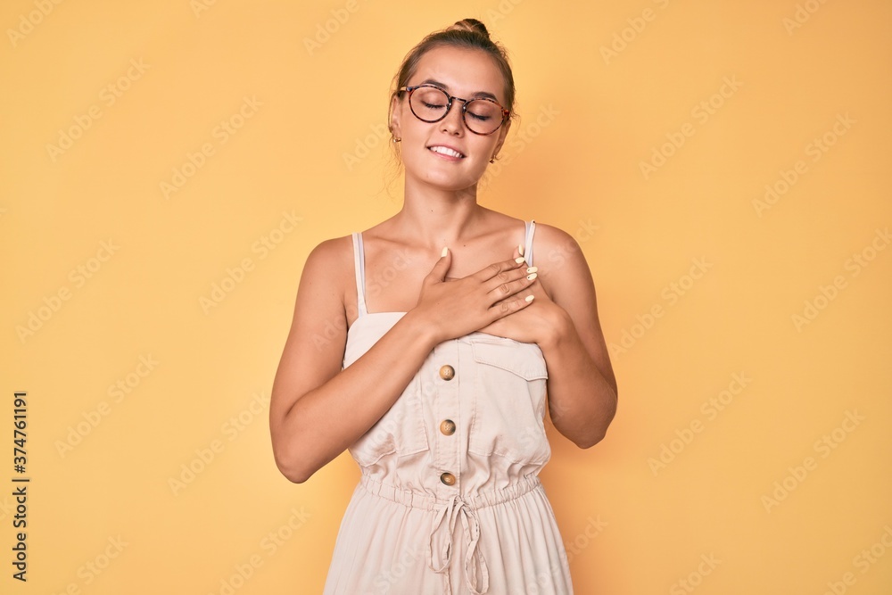 Obraz premium Beautiful caucasian woman wearing summer dress smiling with hands on chest with closed eyes and grateful gesture on face. health concept.