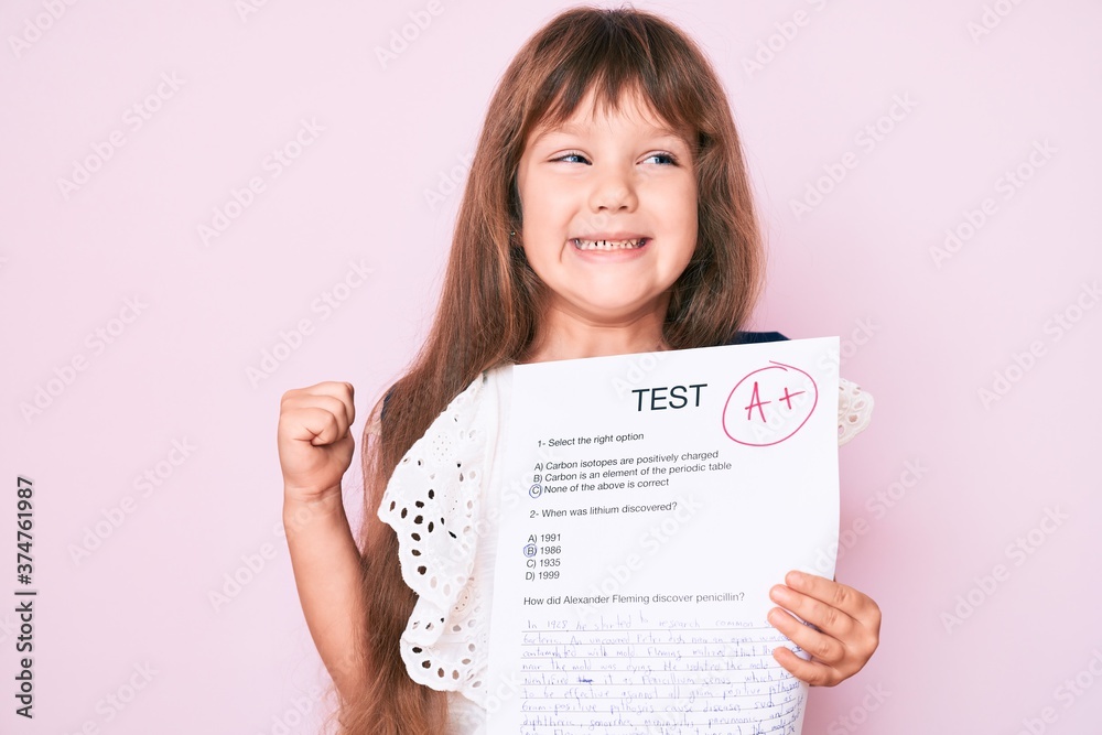 Little caucasian kid girl with long hair showing a passed exam from primary school screaming proud, celebrating victory and success very excited with raised arm Little caucasian kid girl with long hair showing a passed exam from primary school screaming proud, celebrating victory and success very excited with raised arm