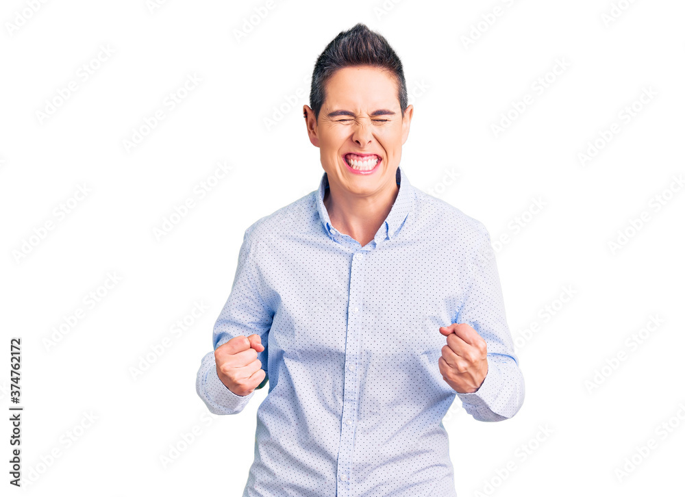 Young woman with short hair wearing business clothes excited for success with arms raised and eyes closed celebrating victory smiling. winner concept. Young woman with short hair wearing business clothes excited for success with arms raised and eyes closed celebrating victory smiling. winner concept.