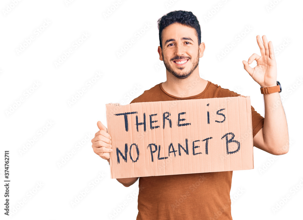 Young hispanic man holding there is no planet b banner doing ok sign with fingers, smiling friendly gesturing excellent symbol Young hispanic man holding there is no planet b banner doing ok sign with fingers, smiling friendly gesturing excellent symbol