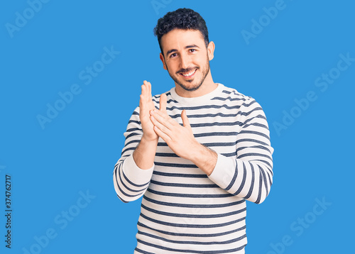 Young hispanic man wearing casual clothes clapping and applauding happy and joyful, smiling proud hands together