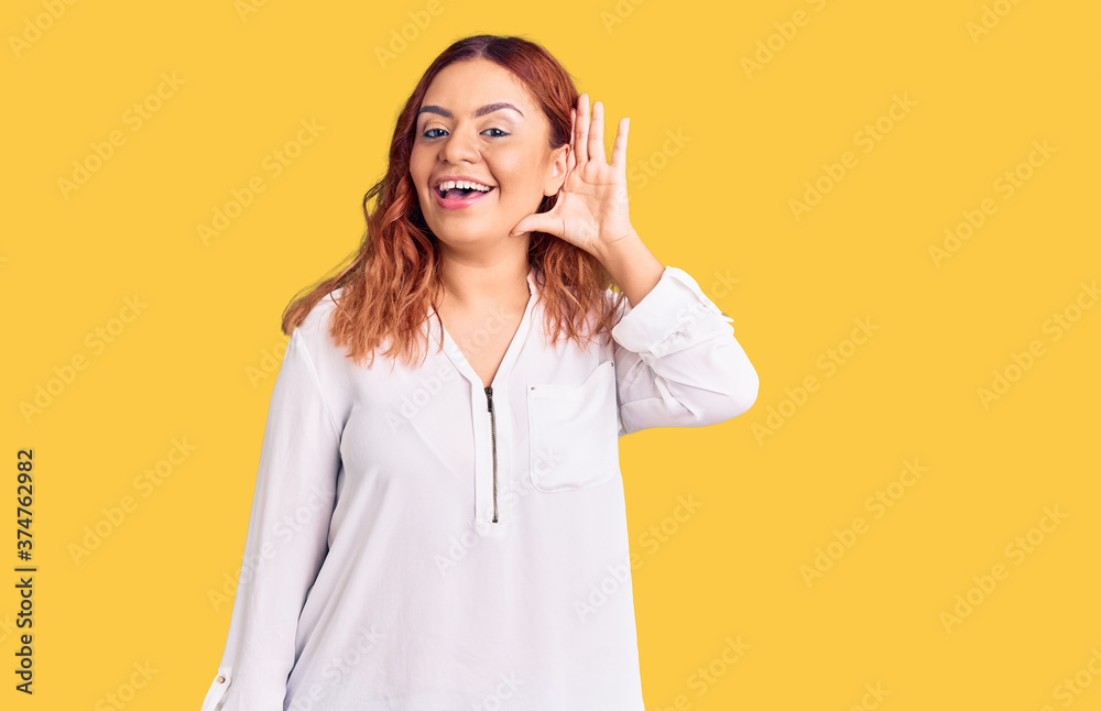 Young latin woman wearing casual clothes smiling with hand over ear listening an hearing to rumor or gossip. deafness concept. Young latin woman wearing casual clothes smiling with hand over ear listening an hearing to rumor or gossip. deafness concept.