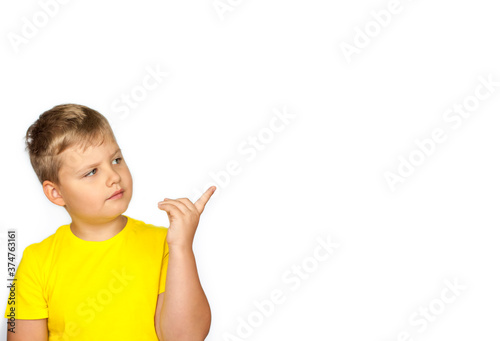 A portrait of a boy in a bright yellow t-shirt pointed up. A teenager has an idea. The child is isolated on a white background. Success, bright idea, creative ideas and innovative technology concepts.