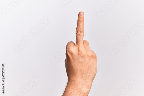 Hand of caucasian young man showing fingers over isolated white background showing provocative and rude gesture doing fuck you symbol with middle finger © Krakenimages.com