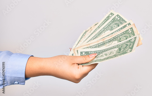 Hand of caucasian young woman holding bunch of dollars banknote over isolated white background