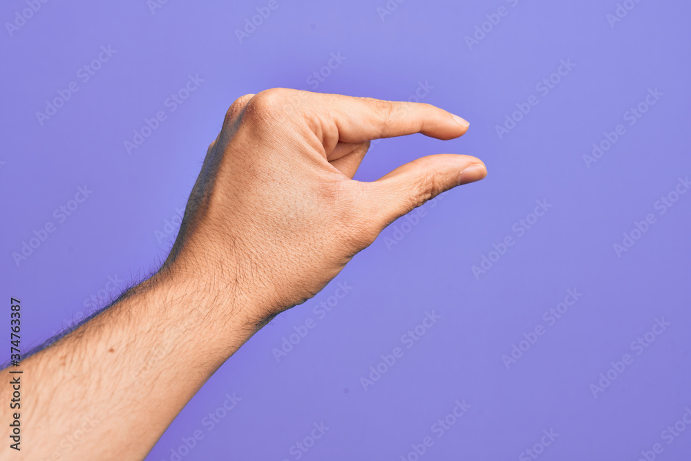 Hand of caucasian young man showing fingers over isolated purple background picking and taking invisible thing, holding object with fingers showing space Hand of caucasian young man showing fingers over isolated purple background picking and taking invisible thing, holding object with fingers showing space