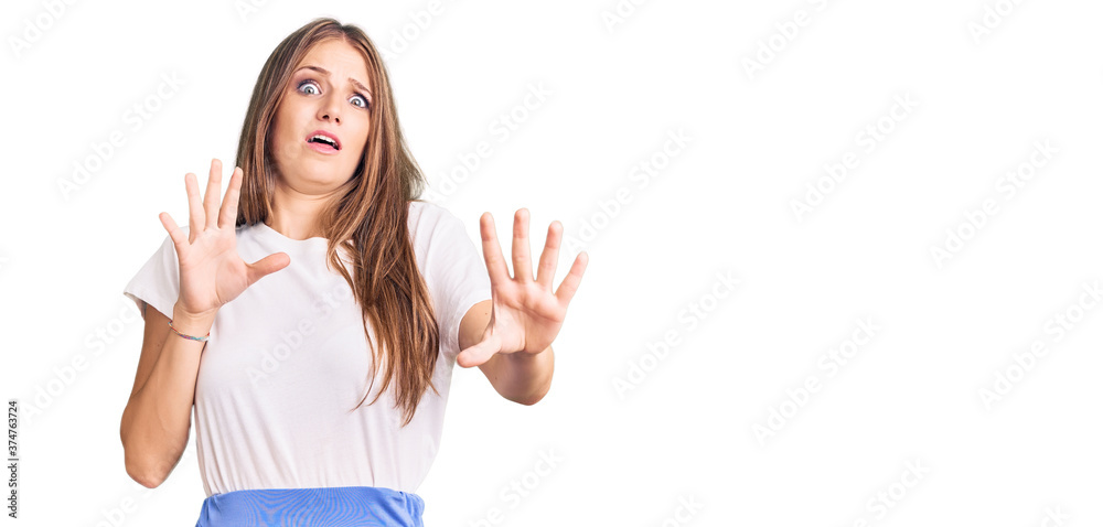 Young beautiful blonde woman wearing summer style afraid and terrified with fear expression stop gesture with hands, shouting in shock. panic concept. Young beautiful blonde woman wearing summer style afraid and terrified with fear expression stop gesture with hands, shouting in shock. panic concept.