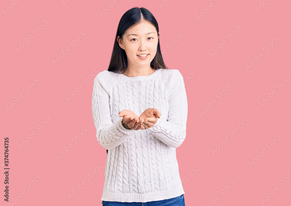 Young beautiful chinese woman wearing casual sweater smiling with hands palms together receiving or giving gesture. hold and protection Young beautiful chinese woman wearing casual sweater smiling with hands palms together receiving or giving gesture. hold and protection