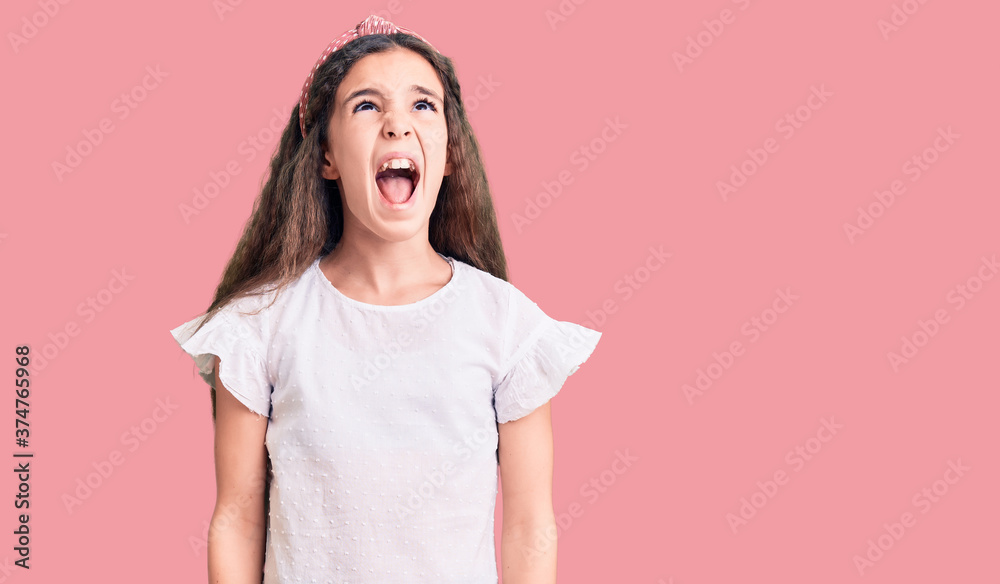 Cute hispanic child girl wearing casual white tshirt angry and mad screaming frustrated and furious, shouting with anger. rage and aggressive concept. Cute hispanic child girl wearing casual white tshirt angry and mad screaming frustrated and furious, shouting with anger. rage and aggressive concept.