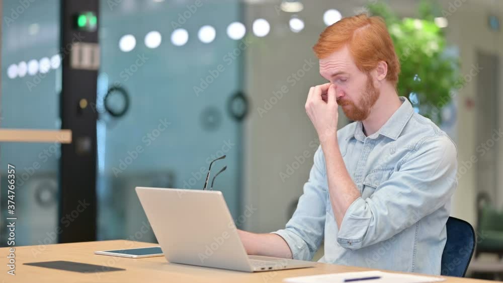 Stressed Casual Redhead Man with Laptop having Headache in Office Stressed Casual Redhead Man with Laptop having Headache in Office