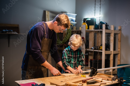 Fotografía a young father and his little son make a toy out of wood in a carpenter's worksh