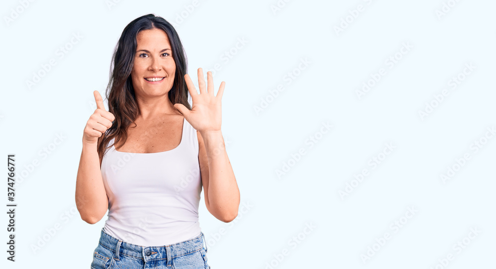 Young beautiful brunette woman wearing casual sleeveless t-shirt showing and pointing up with fingers number six while smiling confident and happy. Young beautiful brunette woman wearing casual sleeveless t-shirt showing and pointing up with fingers number six while smiling confident and happy.