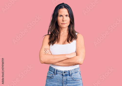 Young beautiful brunette woman wearing casual sleeveless t-shirt skeptic and nervous, disapproving expression on face with crossed arms. negative person.