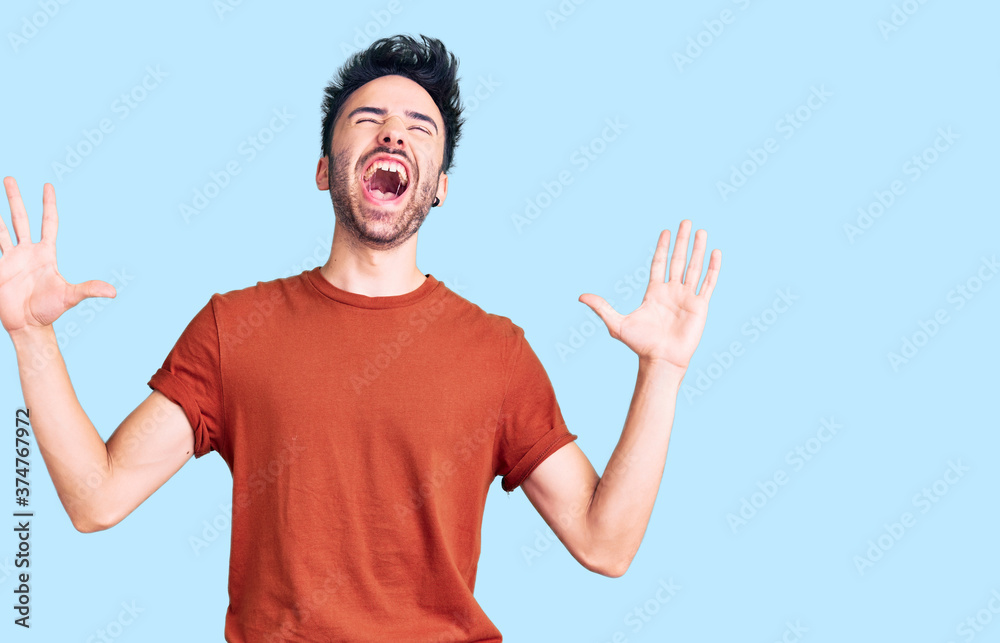 Young hispanic man wearing casual clothes crazy and mad shouting and yelling with aggressive expression and arms raised. frustration concept. Young hispanic man wearing casual clothes crazy and mad shouting and yelling with aggressive expression and arms raised. frustration concept.