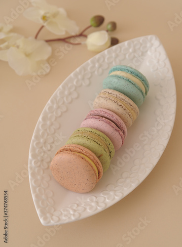 Macarons in white plate on beige background. photo