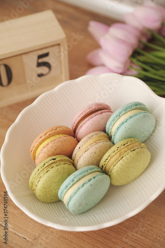 Macarons in white plate on beige background. photo