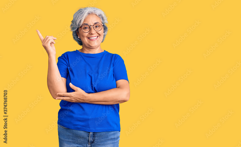 Senior woman with gray hair wearing casual clothes and glasses smiling happy pointing with hand and finger to the side Senior woman with gray hair wearing casual clothes and glasses smiling happy pointing with hand and finger to the side