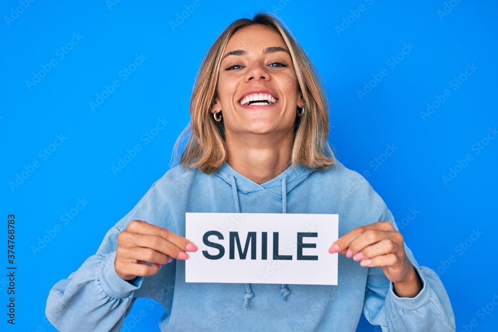 Beautiful caucasian woman holding smile text smiling and laughing hard out loud because funny crazy joke. Beautiful caucasian woman holding smile text smiling and laughing hard out loud because funny crazy joke.