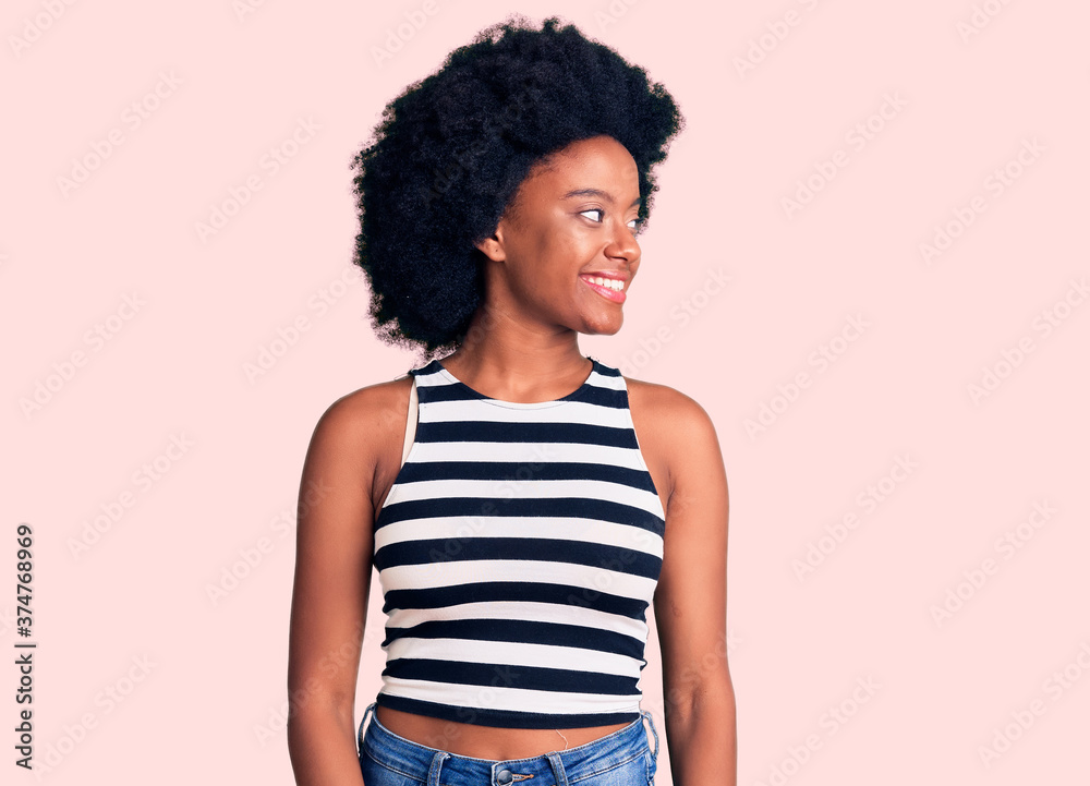 Young african american woman wearing casual clothes looking away to side with smile on face, natural expression. laughing confident. Young african american woman wearing casual clothes looking away to side with smile on face, natural expression. laughing confident.
